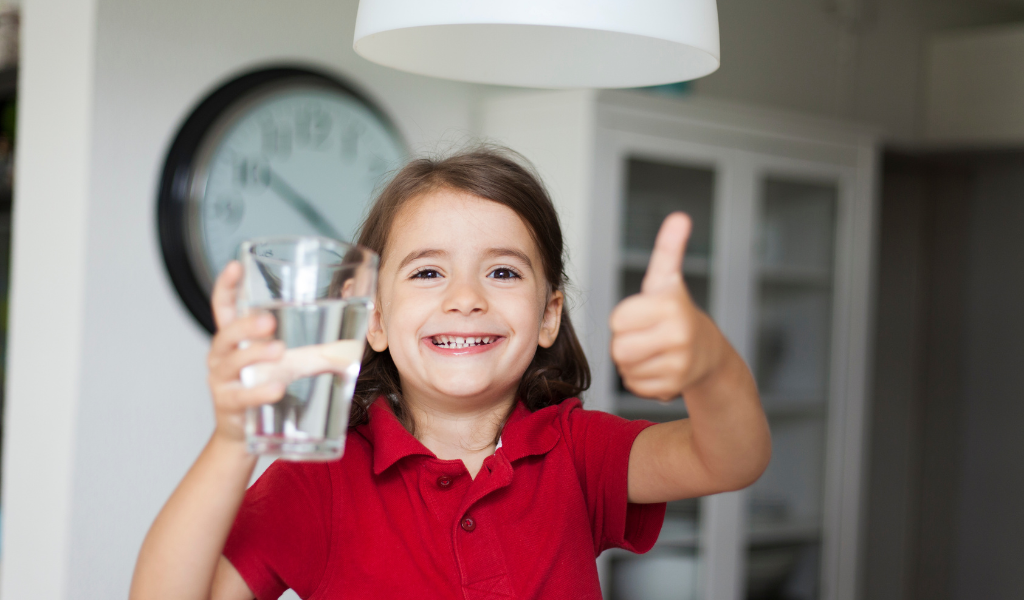 a girl holding a glass of water and thumb up