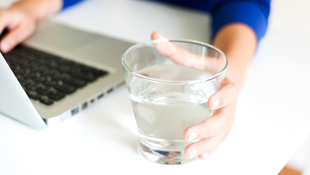 a glass of water next to a computer